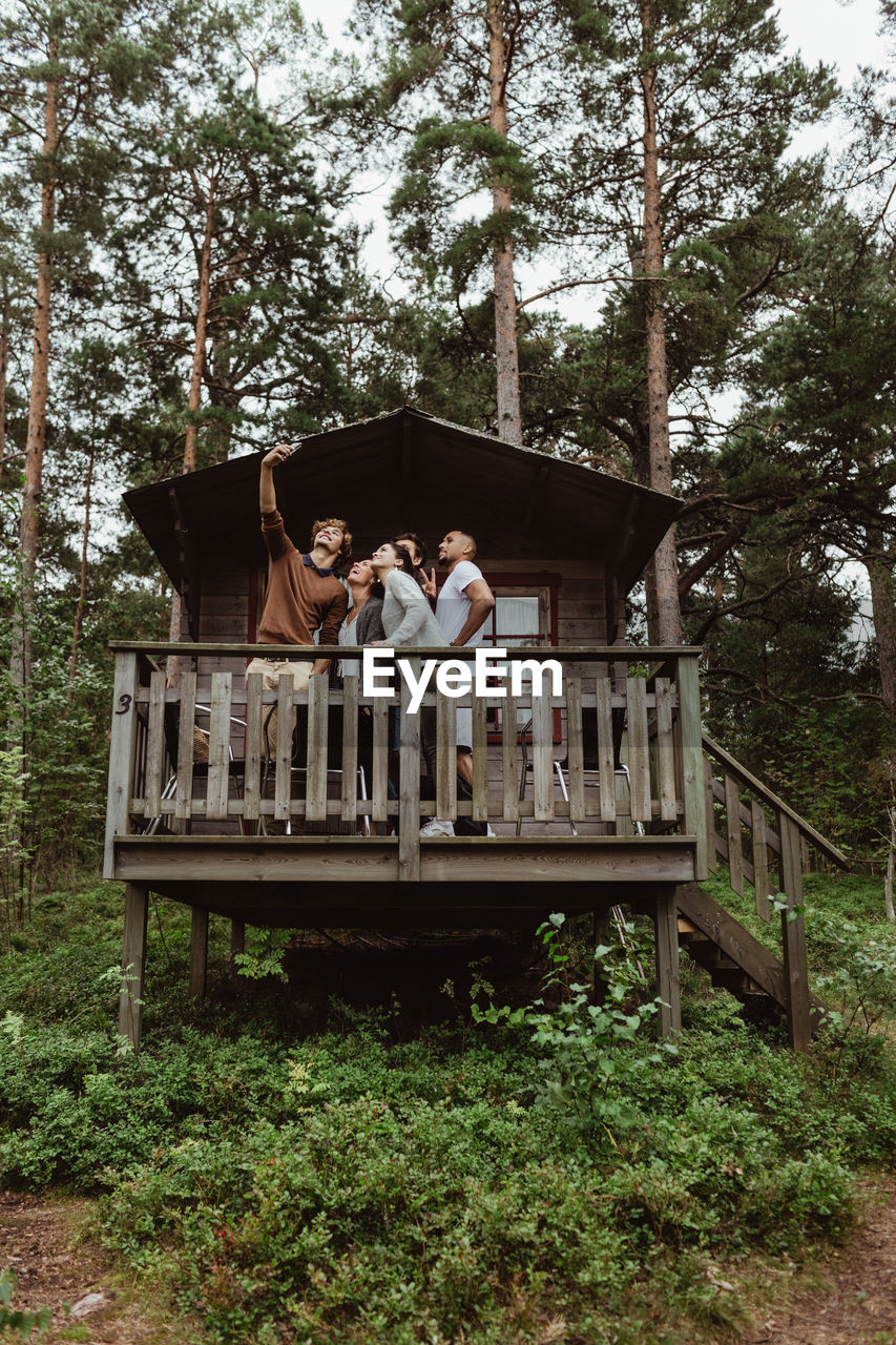 Friends taking selfie with mobile phone while in porch against house