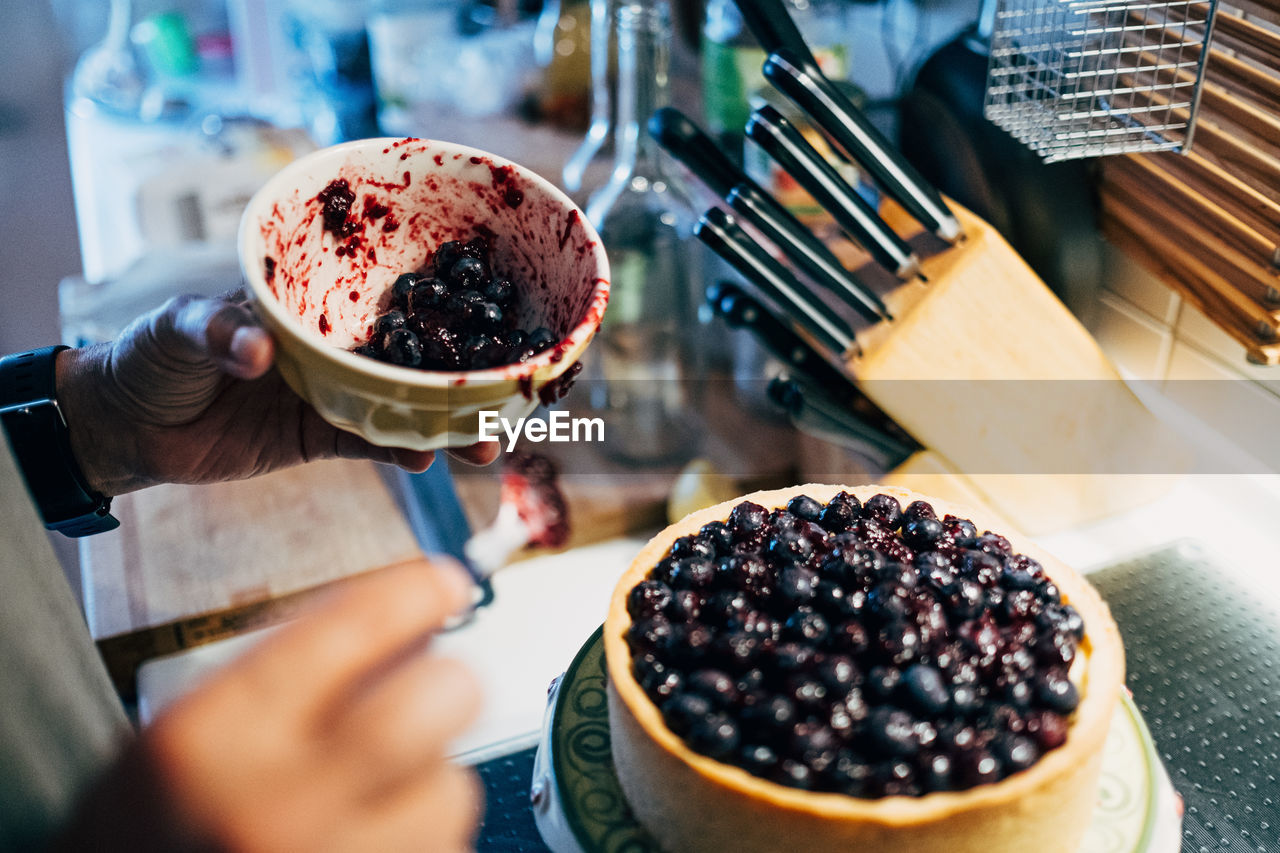 Close-up of hand preparing blueberry cheese cake