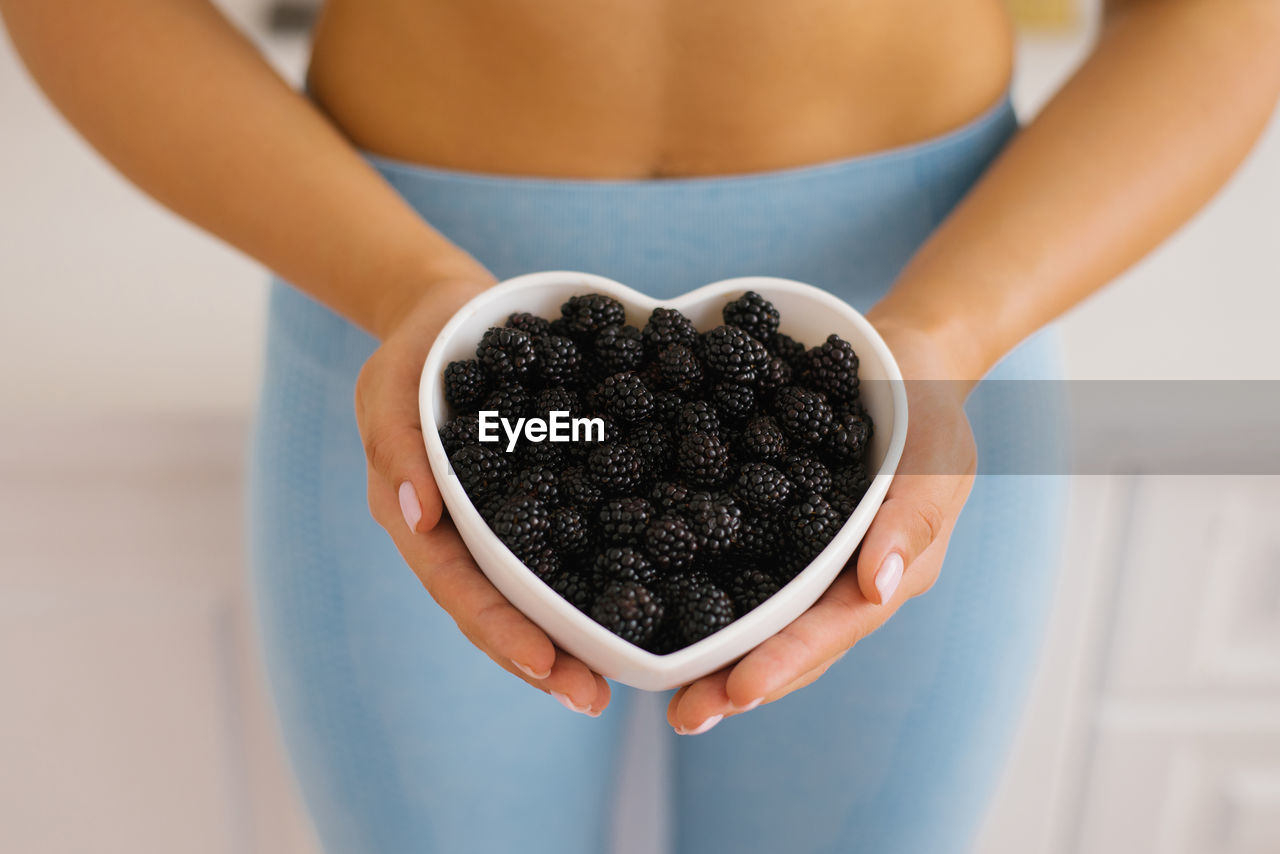 Heart-shaped plate with blackberries in women's hands. the concept of healthy eating