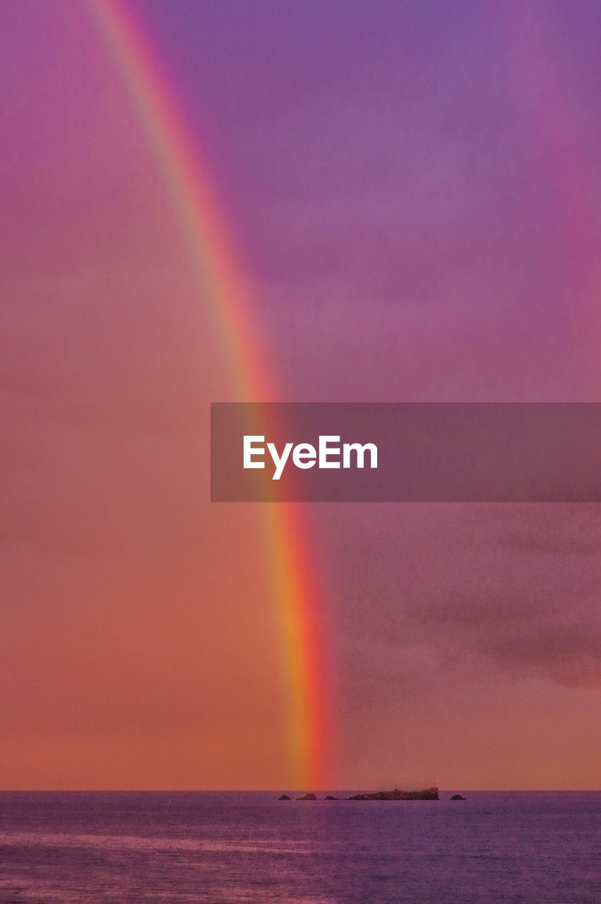 Scenic view of rainbow over sea against sky