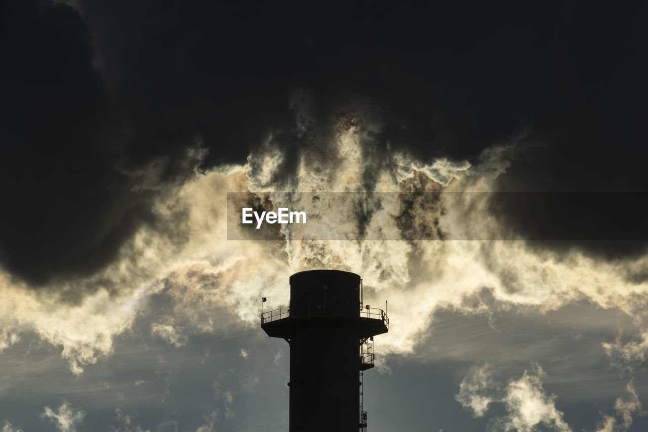 Smoke stacks pour pollution backlit by sunrise