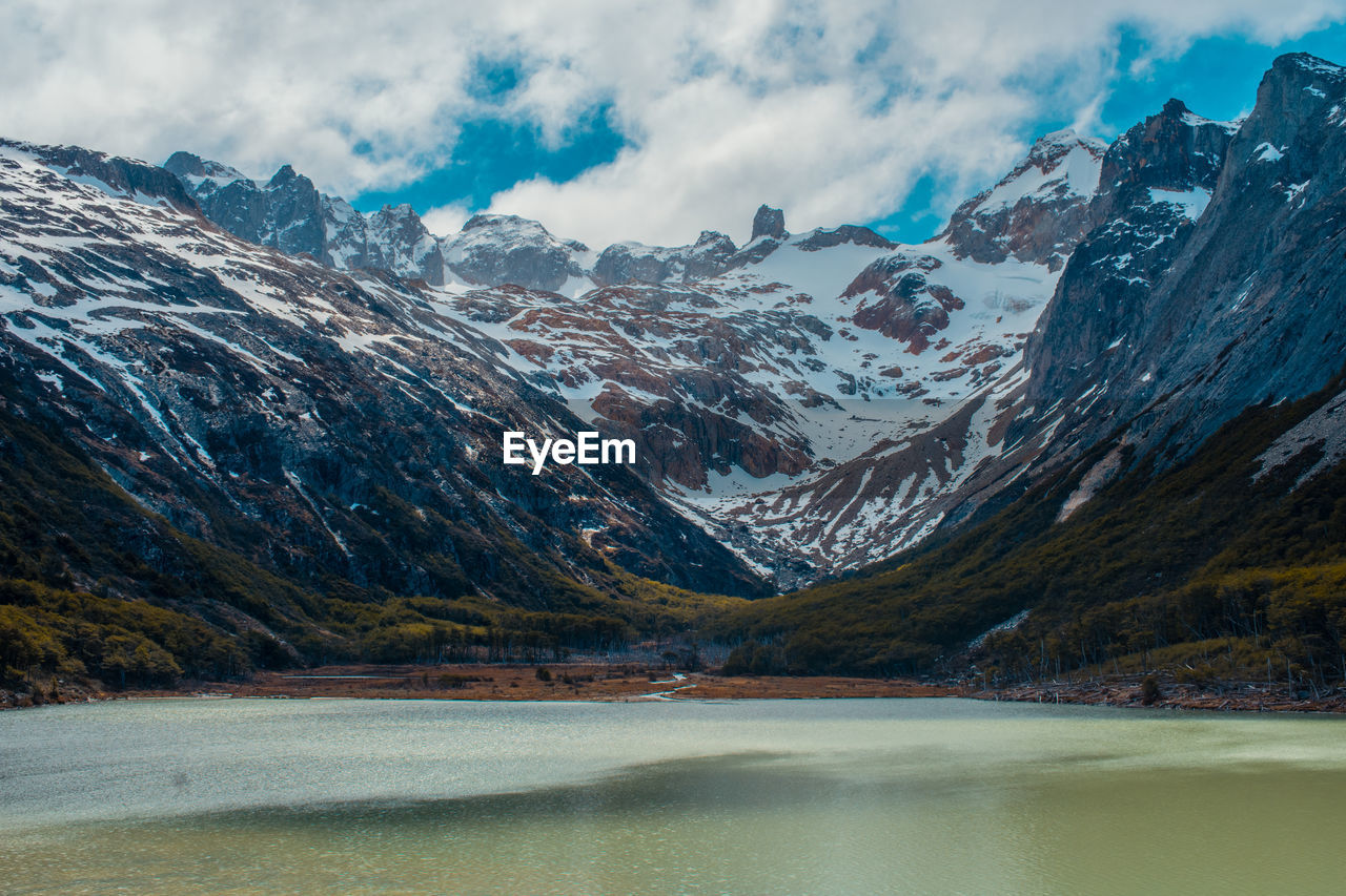 Scenic view of lake by snowcapped mountains against sky