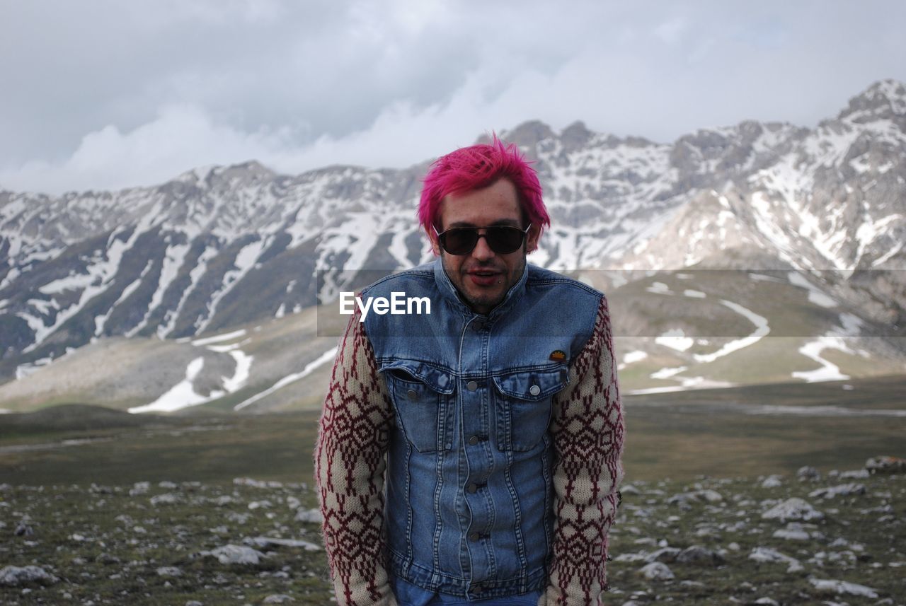 Portrait of man against snow covered mountains and sky