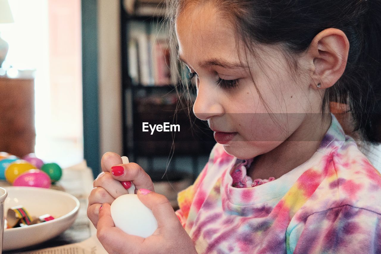 Close-up of girl painting on easter egg at table