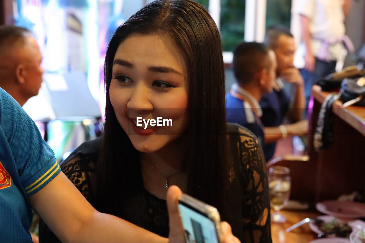 PORTRAIT OF A SMILING GIRL WITH PEOPLE IN BACKGROUND