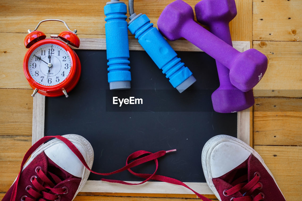 Directly above shot of blackboard with shoes and dumbbells and alarm clock