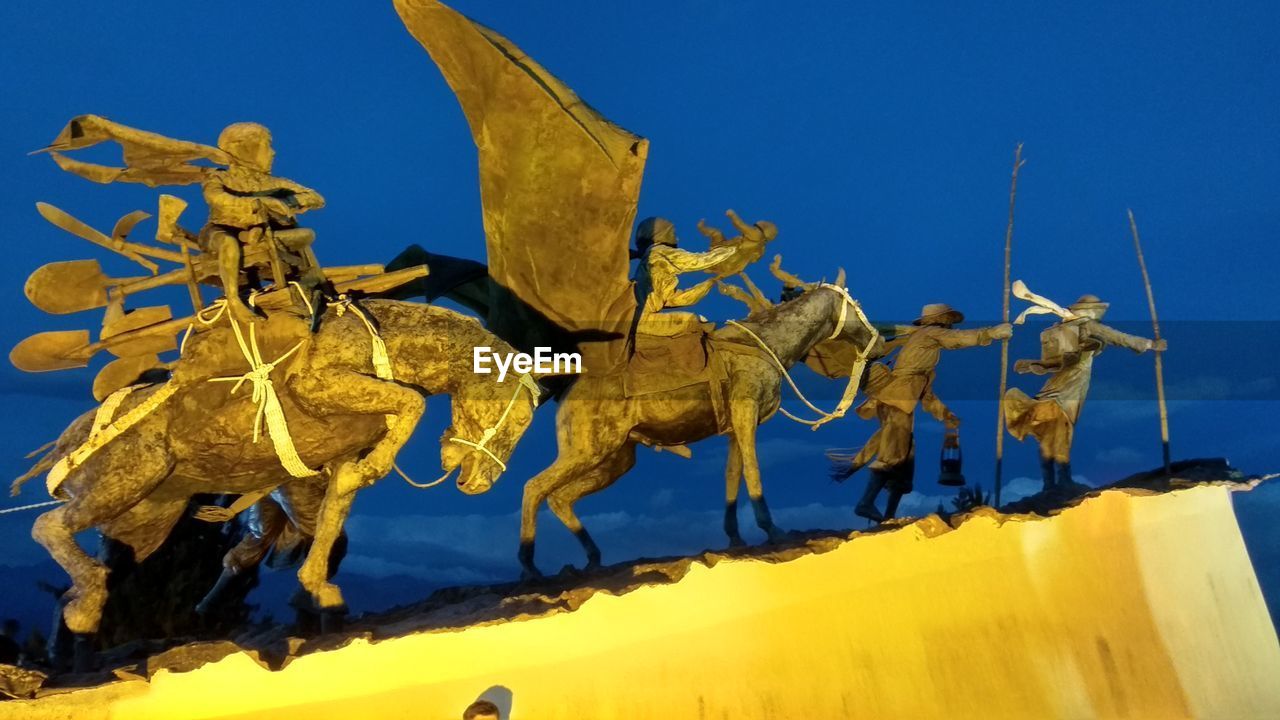 LOW ANGLE VIEW OF YELLOW SCULPTURE AGAINST BLUE SKY