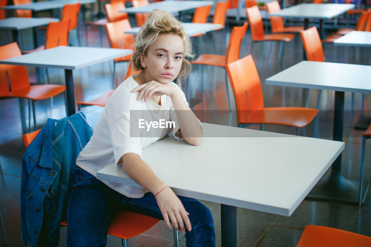 Portrait of young woman sitting on chair in classroom