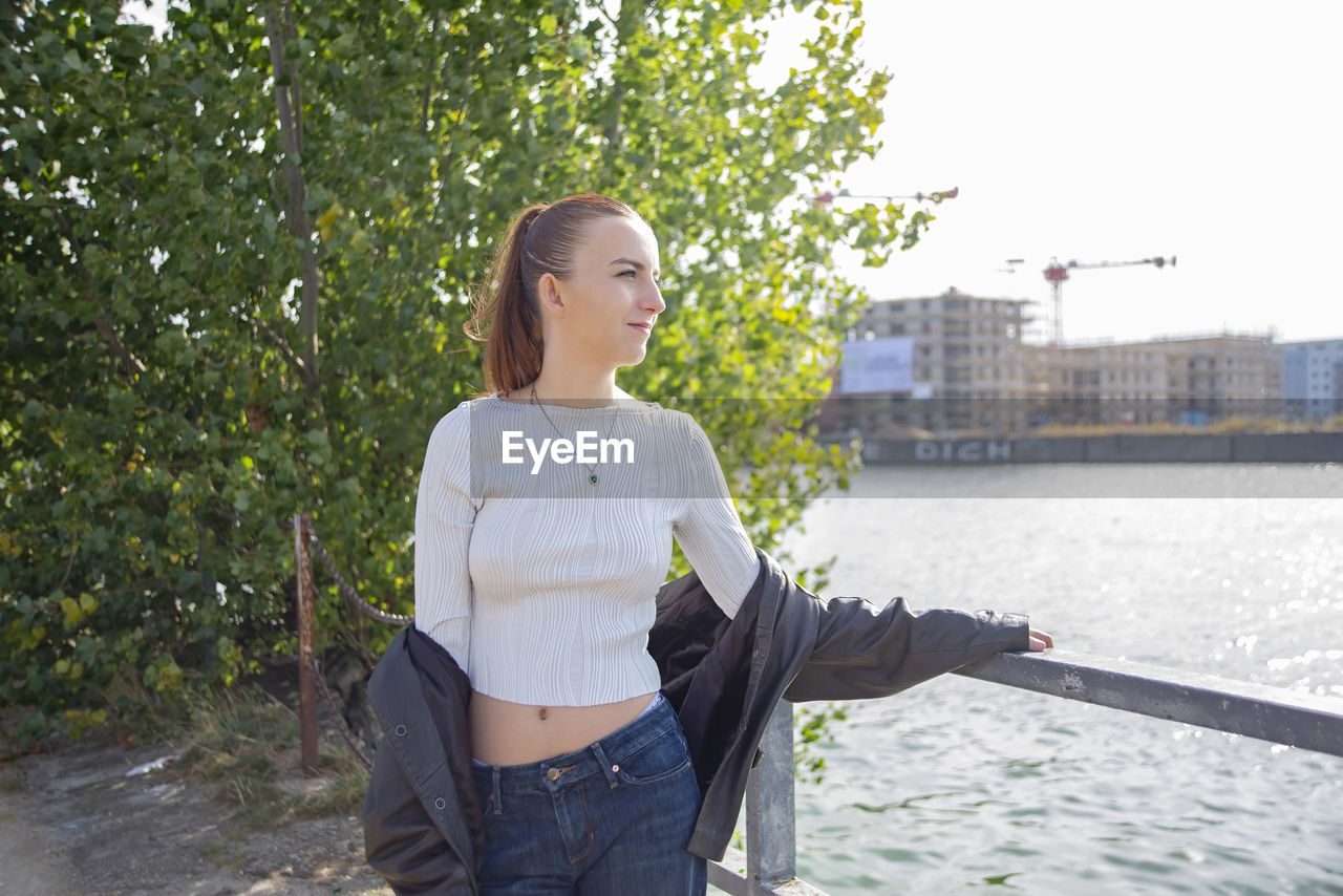 portrait of young woman standing by railing