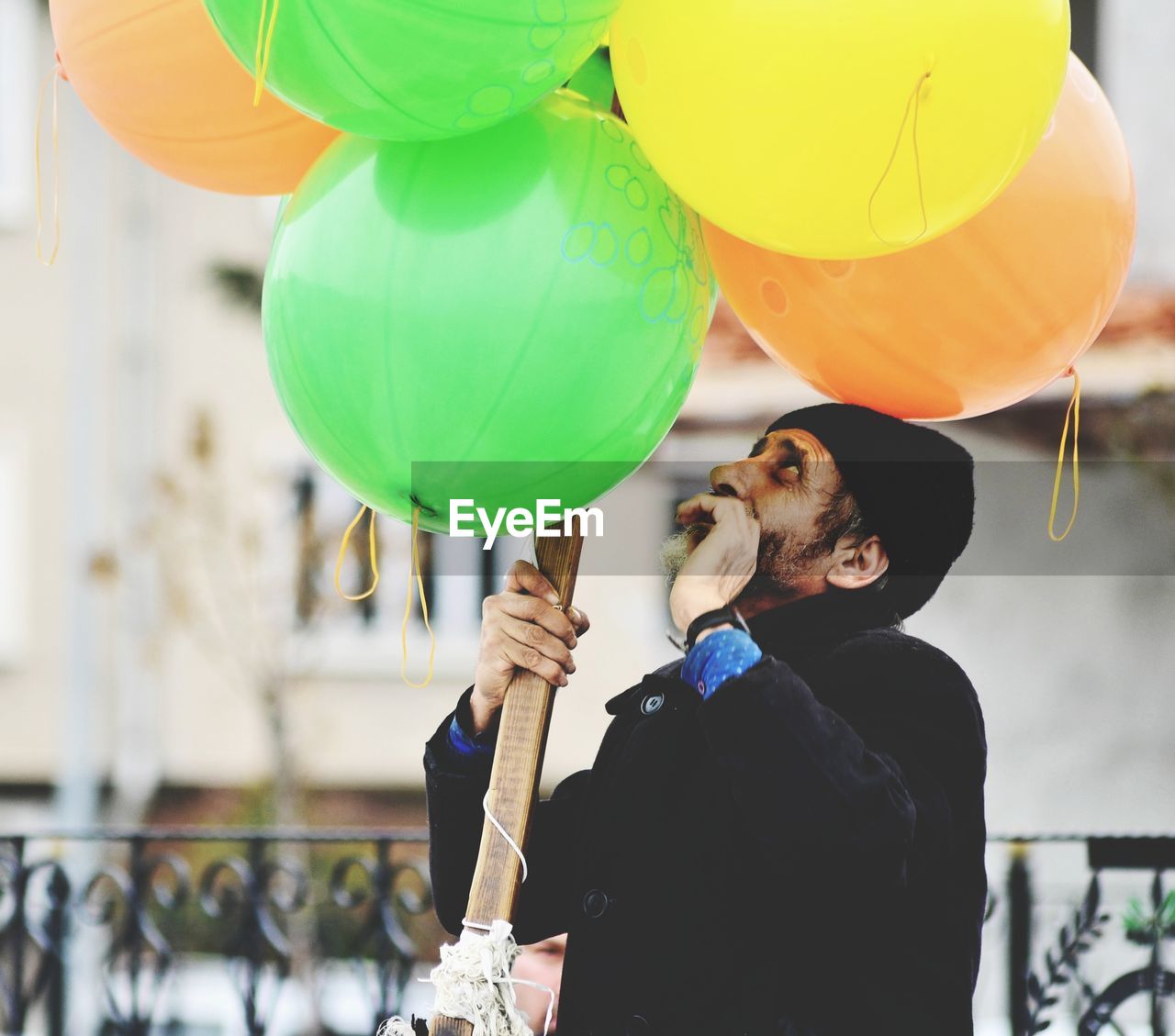 REAR VIEW OF WOMAN HOLDING BALLOONS AT BALLOON