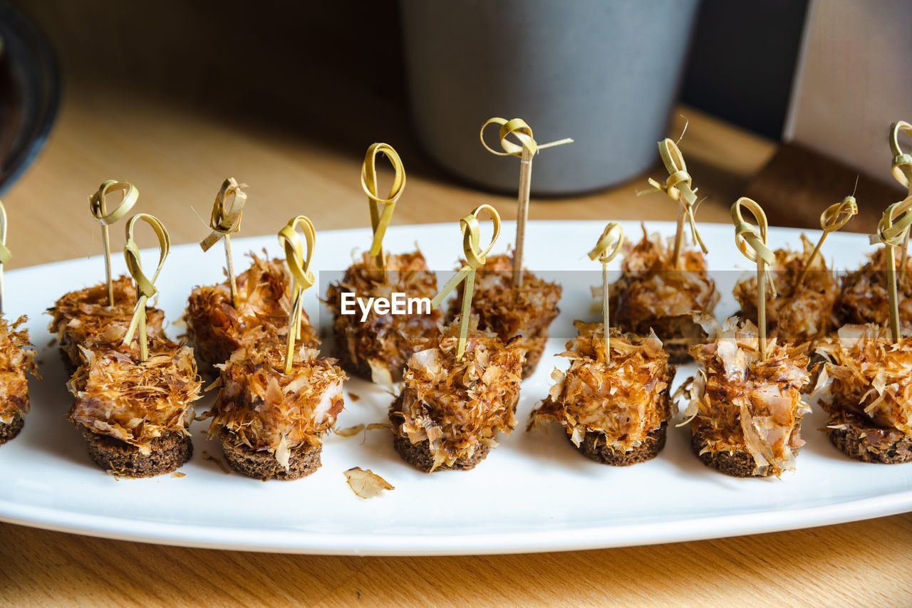 Tuna flakes canapes on a plate on a table. canape set of tuna fish meat on rye bread on skewers.