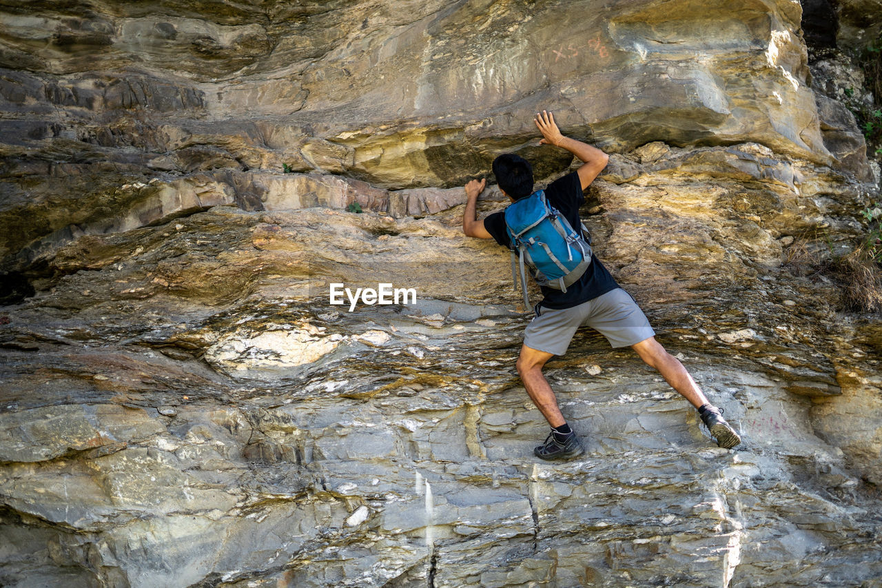 Young boy climbing the rocks wearing a backpack.