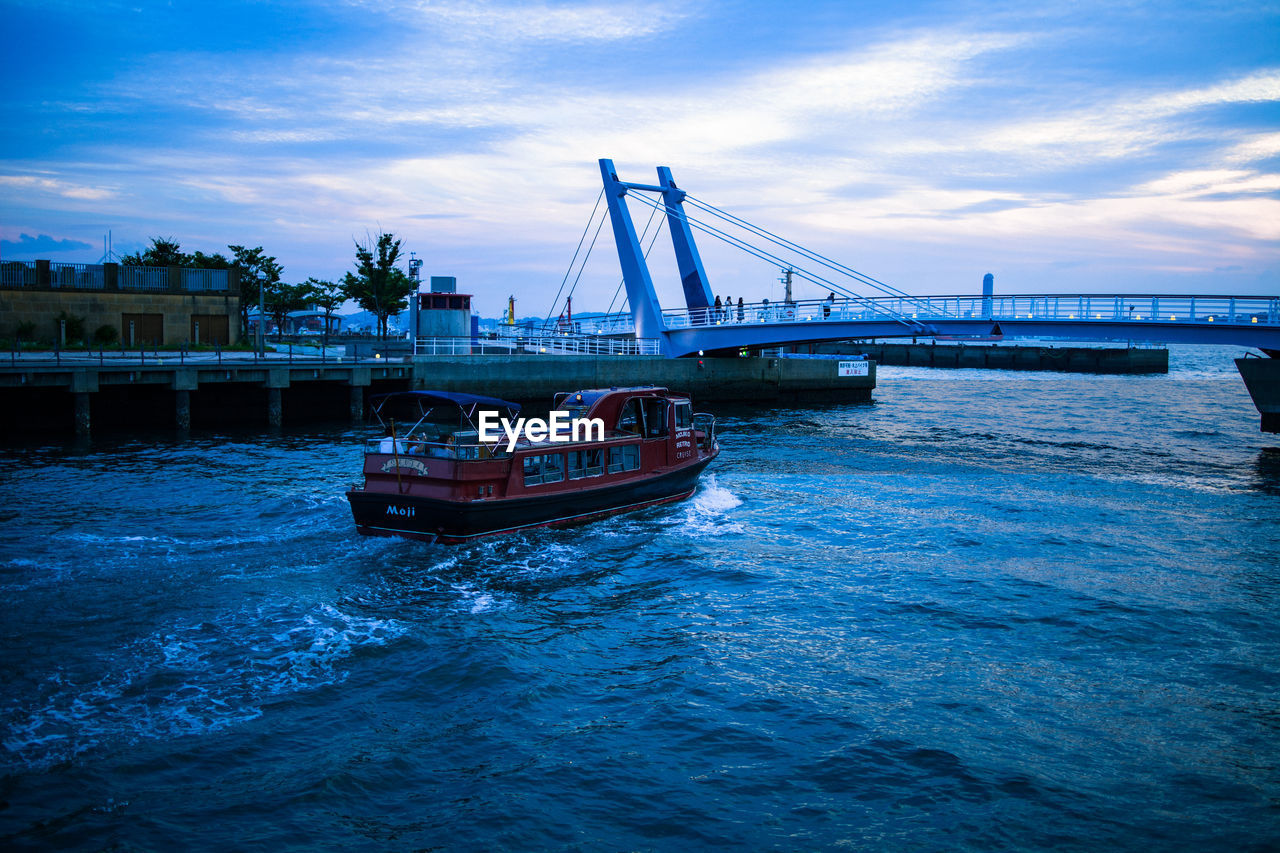 Boat on bridge over river against sky