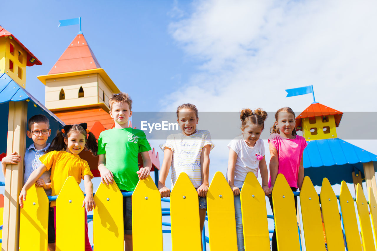 Portrait of cute kids at playground against sky