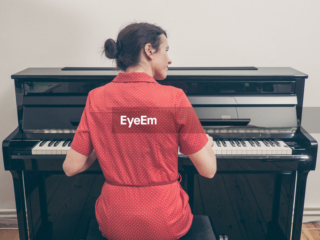 Rear view of woman playing piano at home