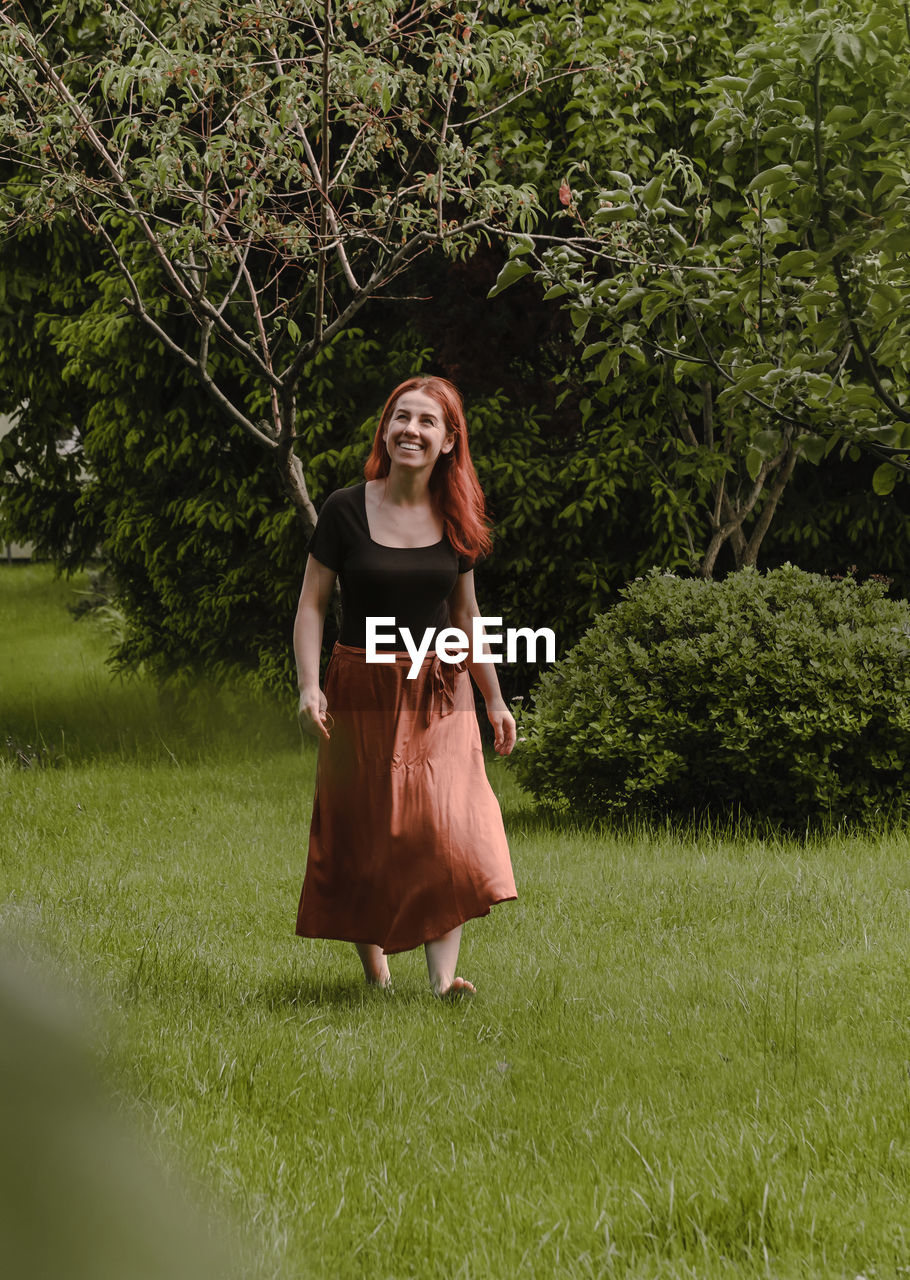 Happy ginger hair woman walking barefoot in the park or garden. freedom and healthy way of life