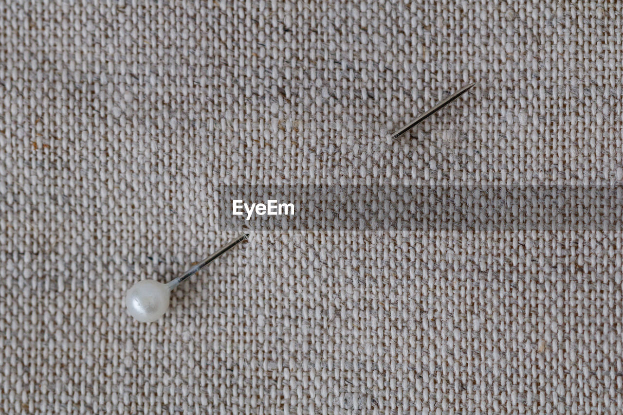 Close-up of straight pin on beige fabric