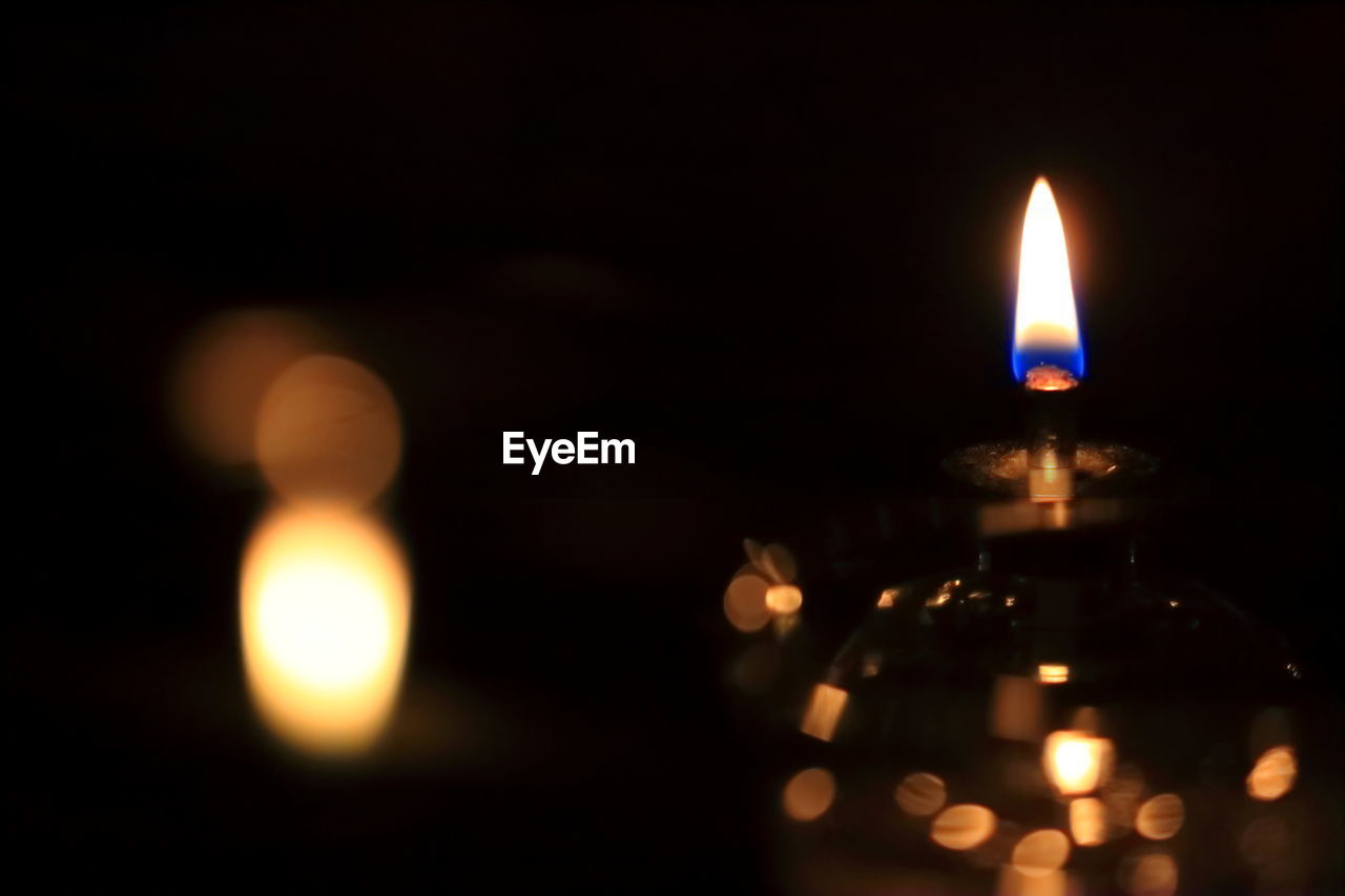 CLOSE-UP OF LIT CANDLES IN DARK ROOM