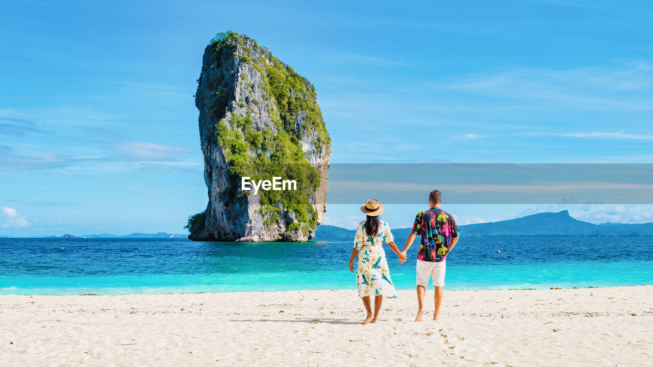 rear view of woman standing on beach against sky