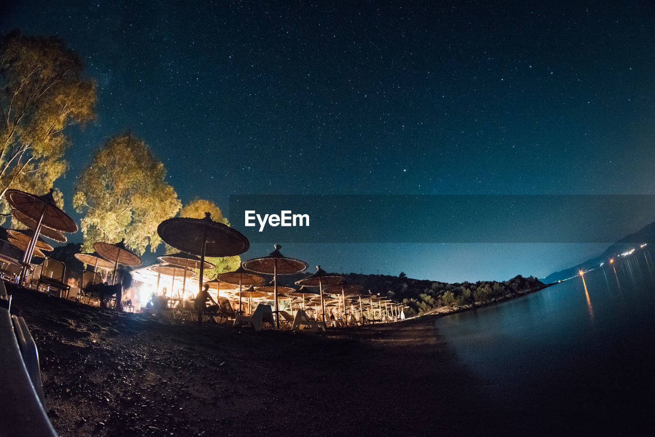 Low angle fish-eye lens shot of parasols against sky at night