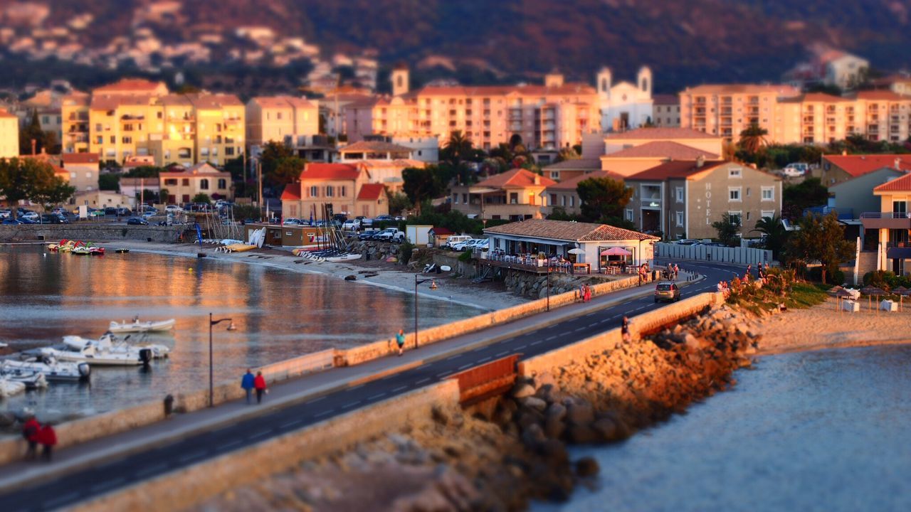 Tilt-shift image of people walking on road amidst sea