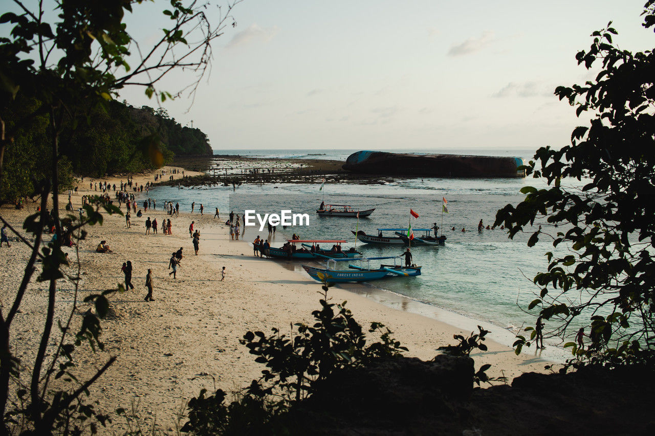 water, sea, beach, body of water, sky, nature, land, tree, nautical vessel, shore, transportation, plant, group of people, coast, mode of transportation, sand, beauty in nature, scenics - nature, large group of people, travel, holiday, vacation, ocean, trip, bay, morning, day, outdoors, crowd, reflection, tranquility, travel destinations, sunlight, leisure activity, tourism, men, cloud, boat, tranquil scene