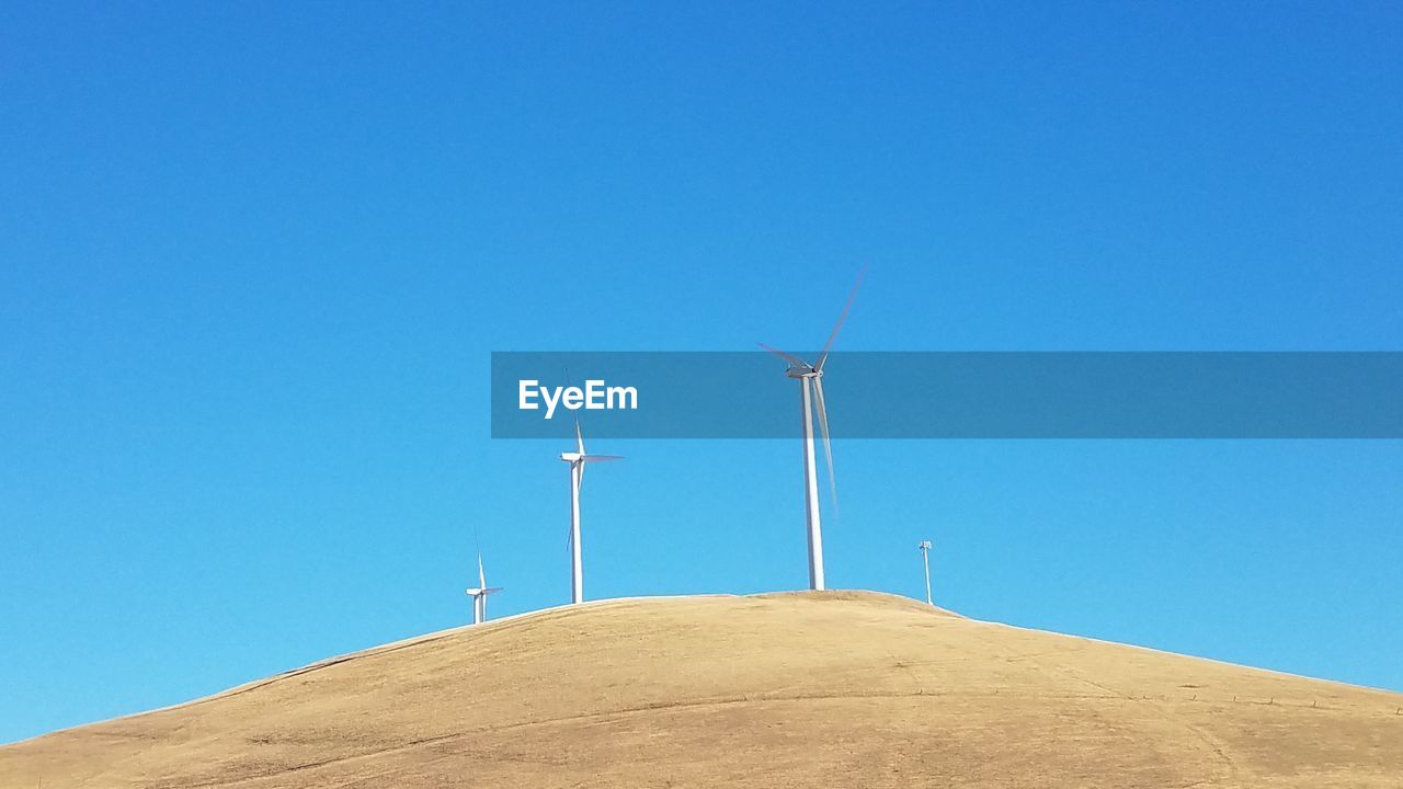 LOW ANGLE VIEW OF WIND TURBINE AGAINST BLUE SKY