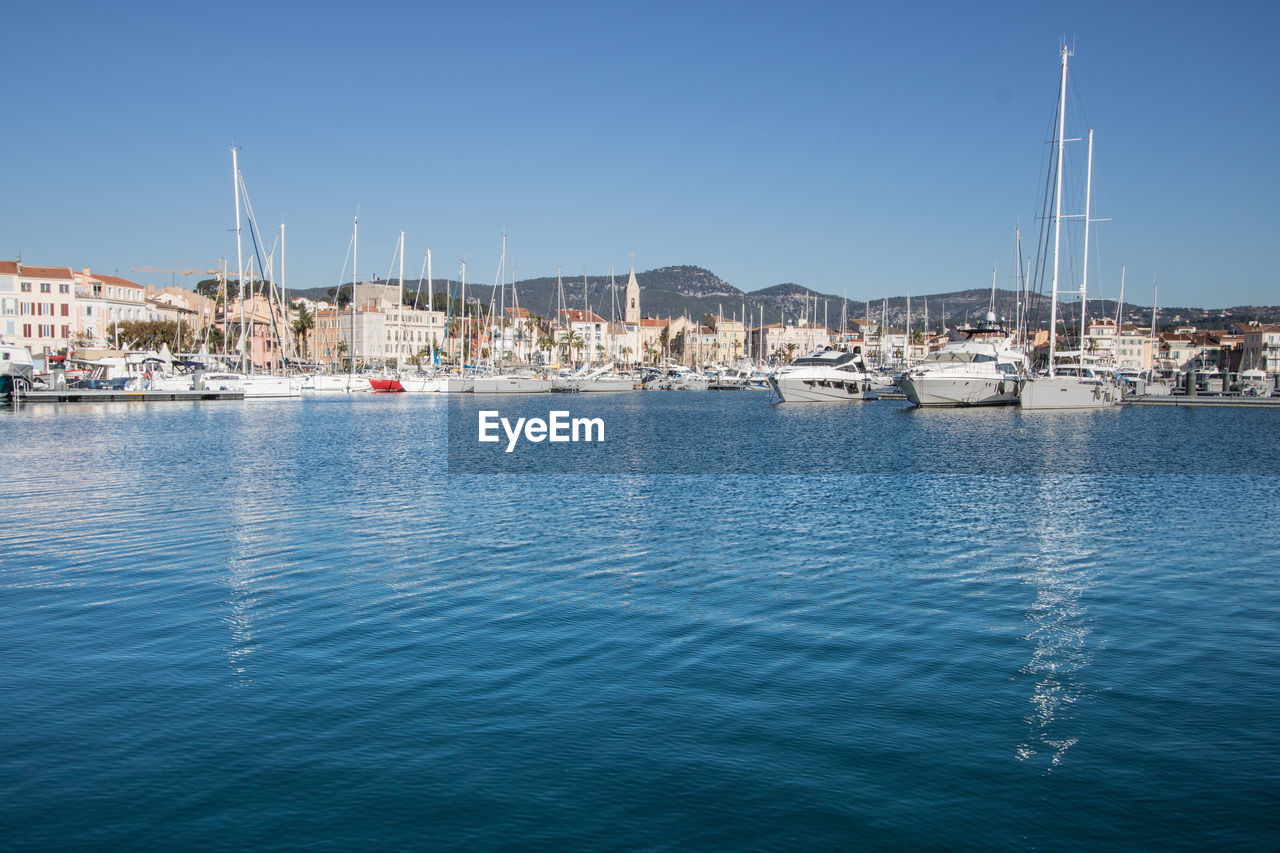 Sailboats moored at harbor against clear sky