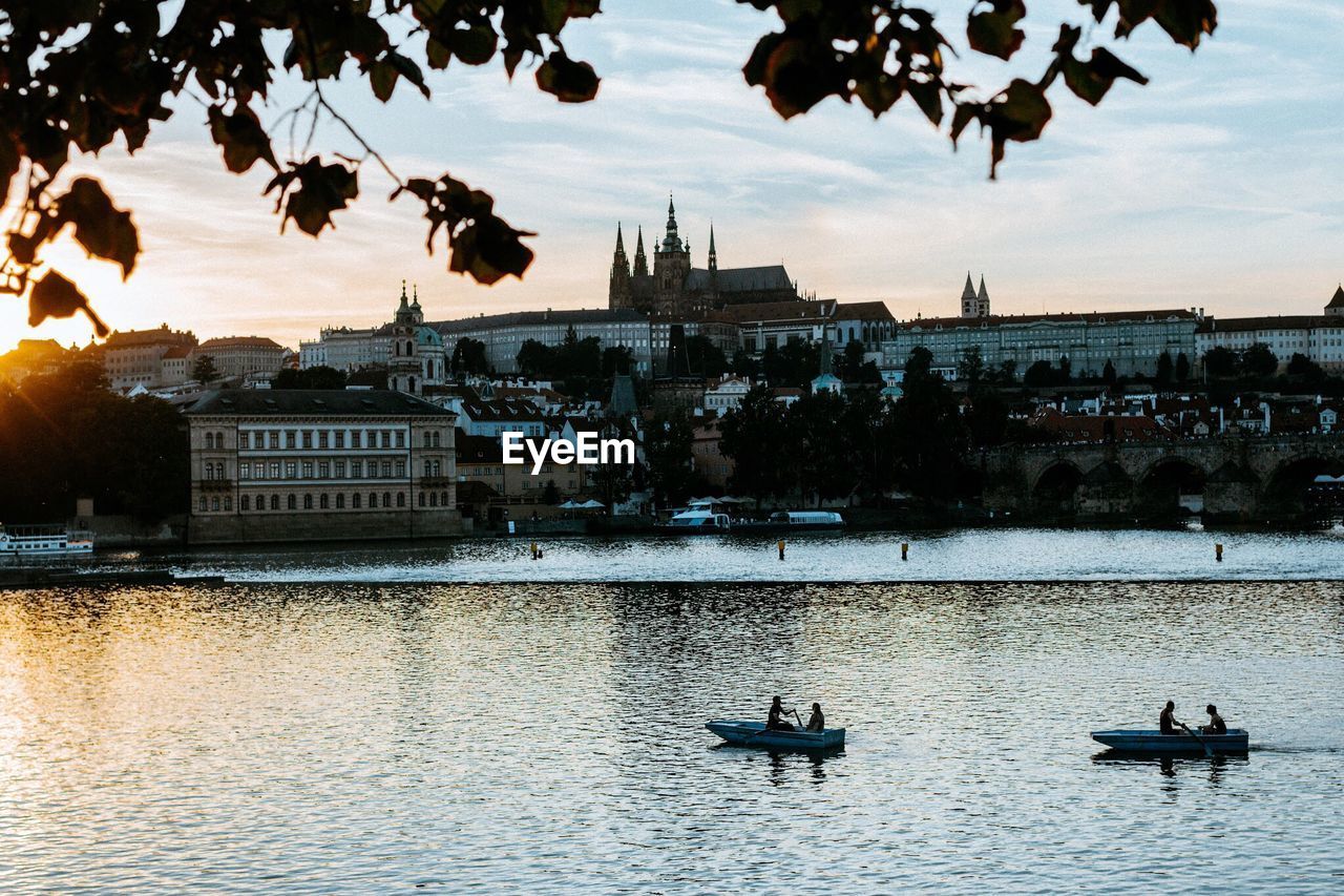 Boats in river against sky in city