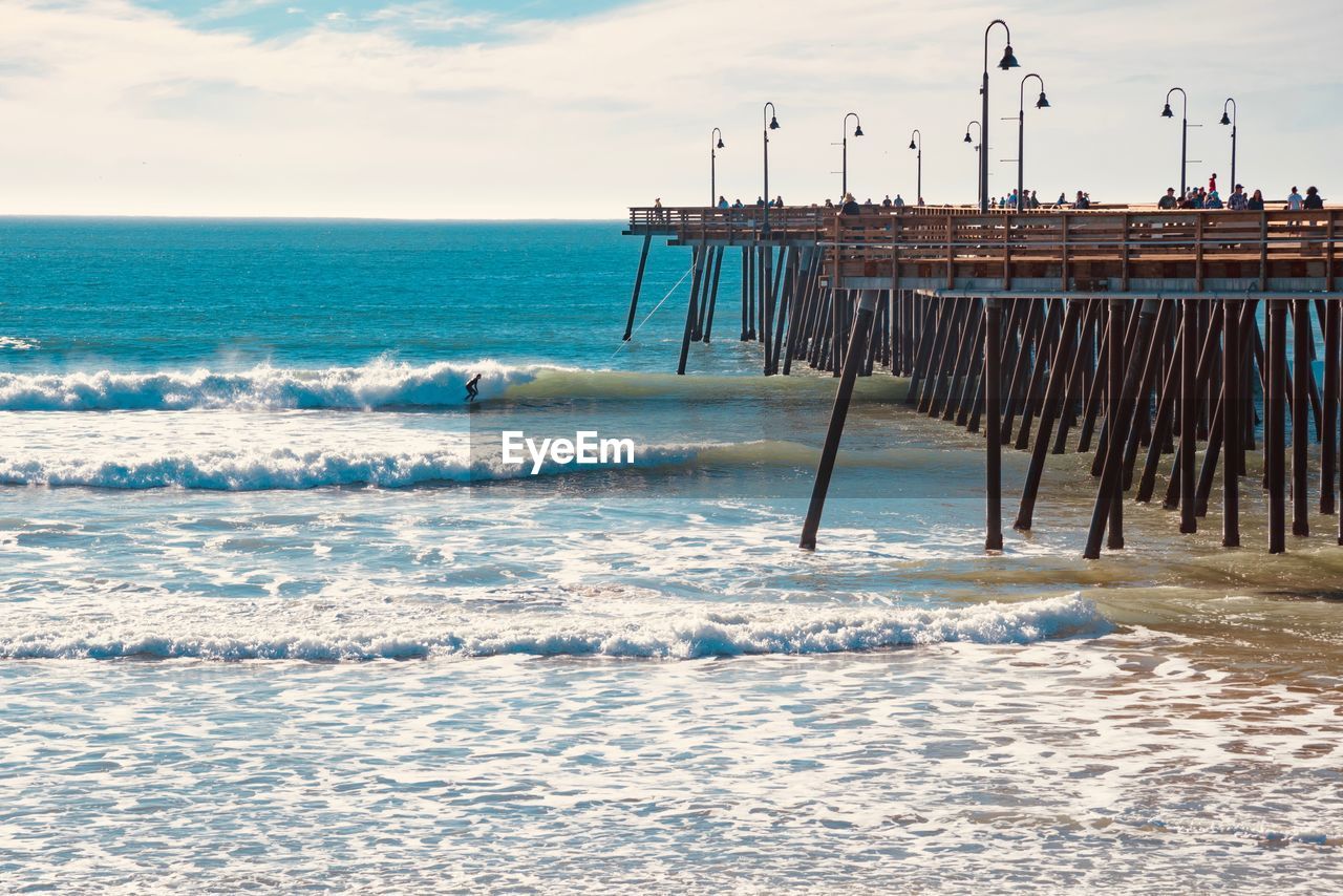 Wooden posts on beach against sky