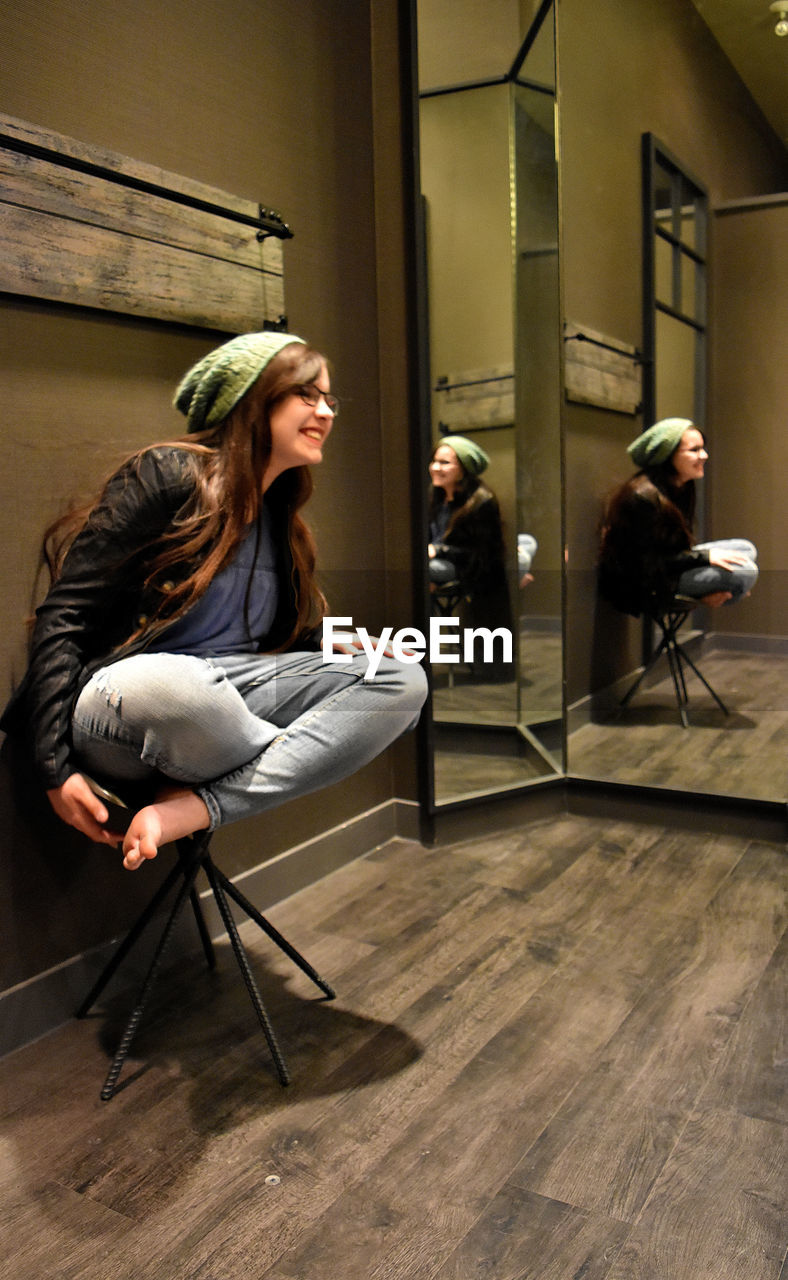 Happy young woman looking away while sitting on stool