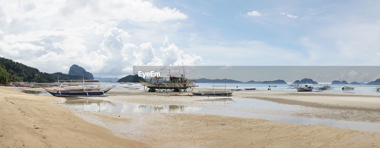 BOATS MOORED ON SHORE AGAINST SKY