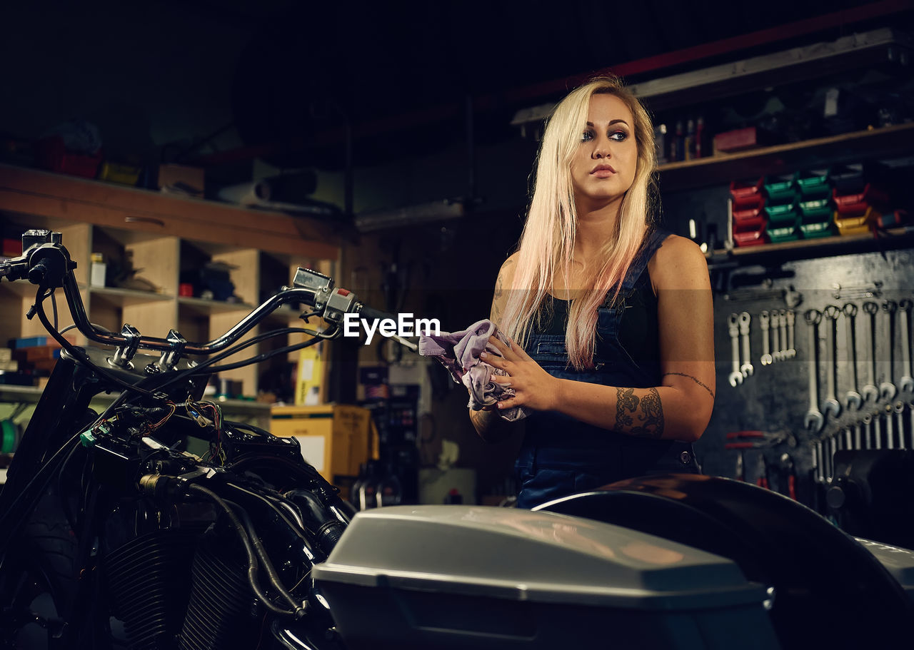 Young woman standing by motorcycle at workshop