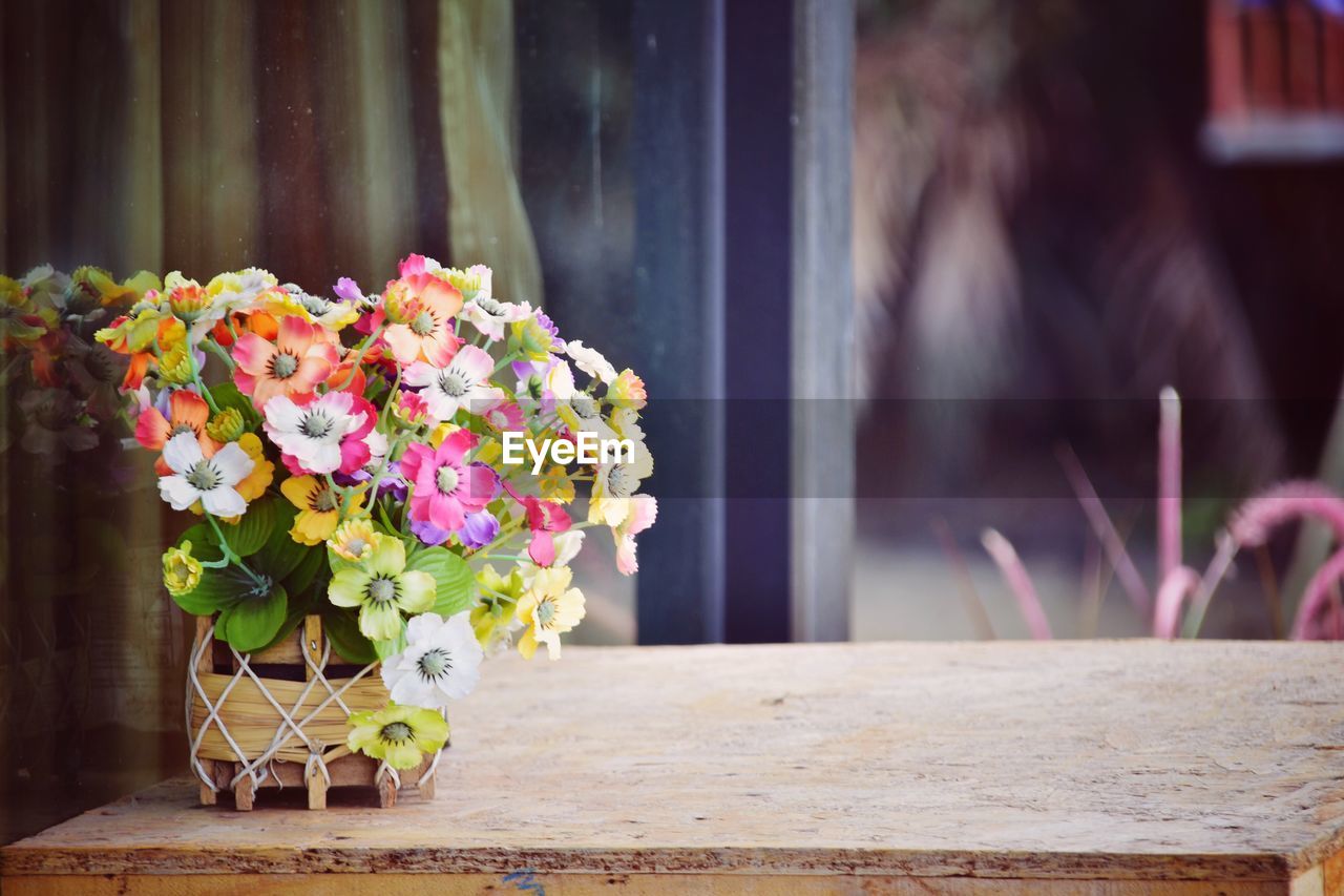 Colorful artificial flowers in pot on table