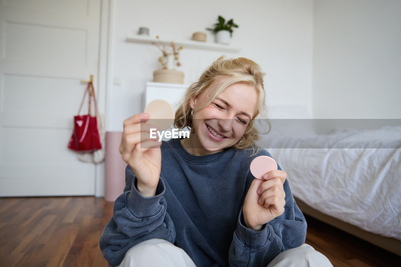 portrait of smiling young woman drinking coffee while sitting on table