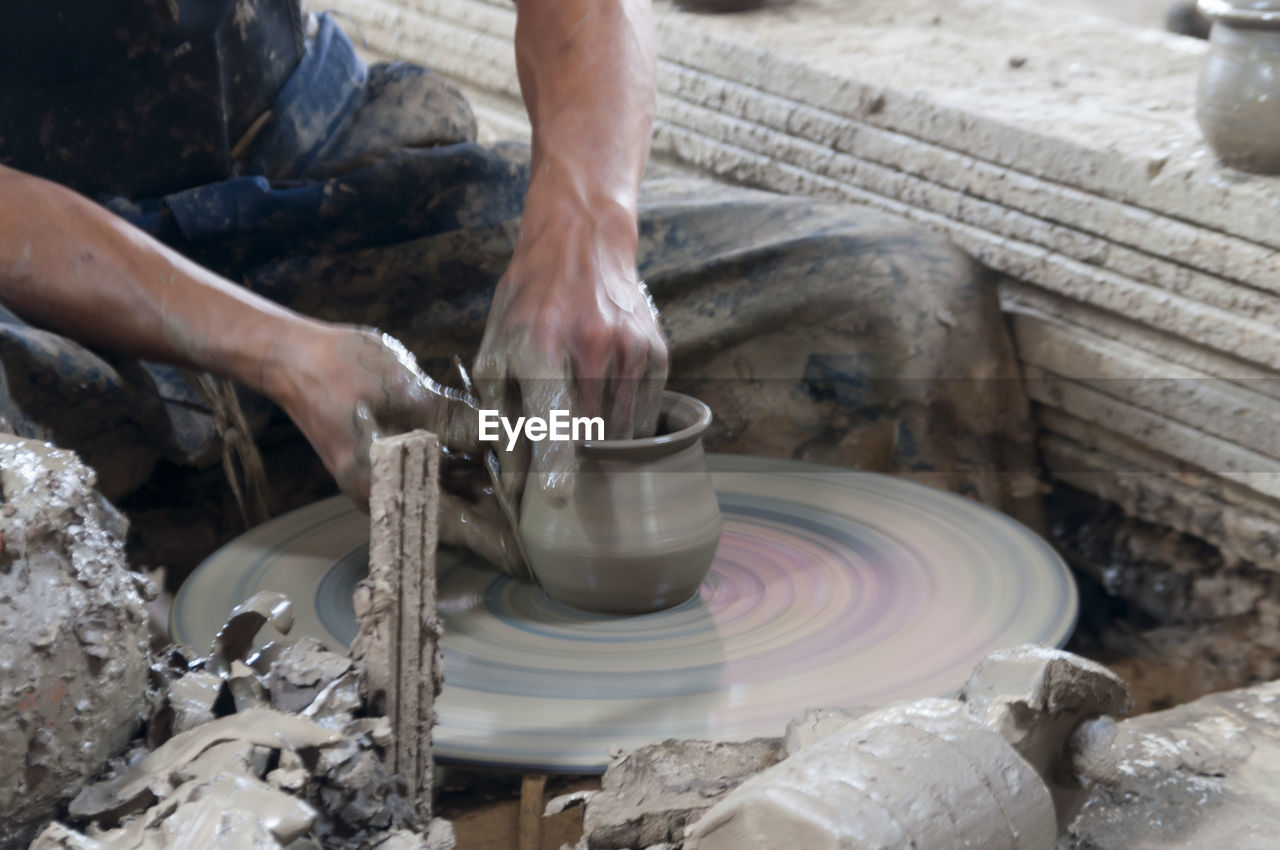 Craftsperson shaping pot on pottery wheel