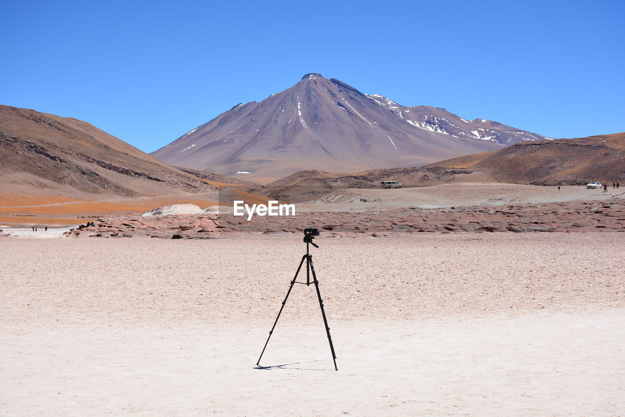 Tripod in desert against clear sky