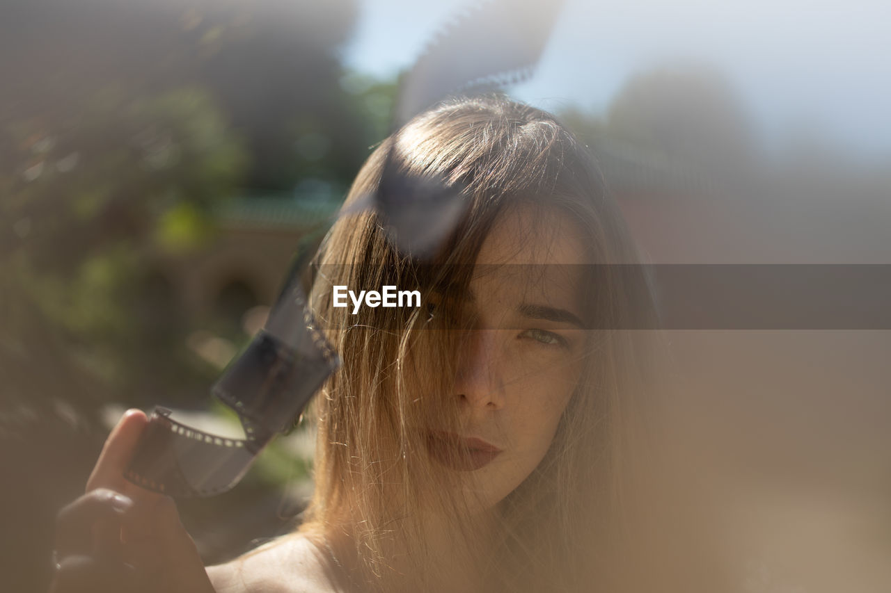 Portrait of young woman holding film reel standing outdoors