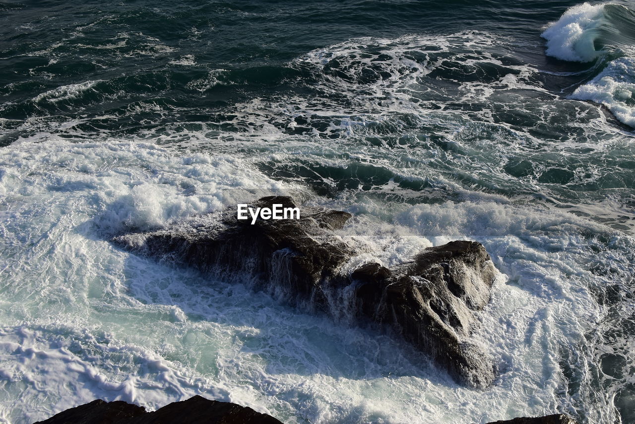 High angle view of waves breaking on rocks