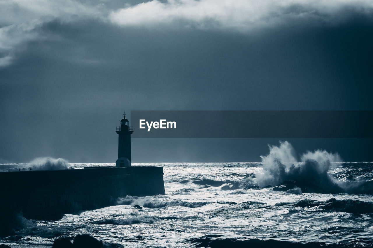 Lonely lighthouse standing agains stormy sea in the evening