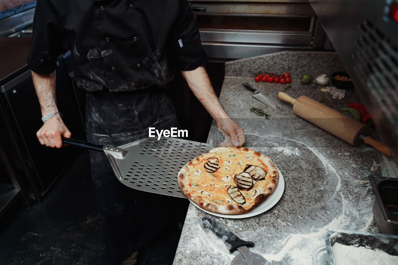 Midsection of man preparing pizza