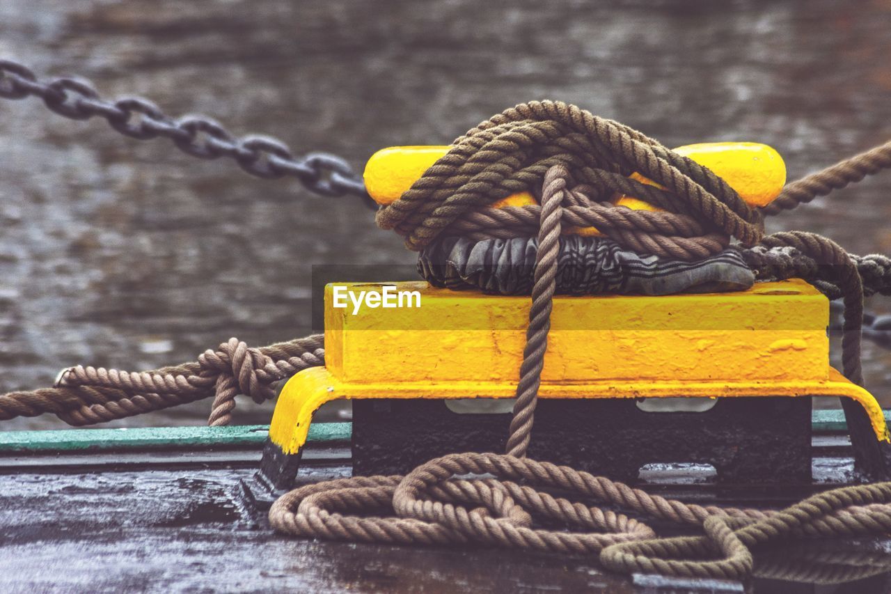 Close-up of rope tied to bollard at harbor