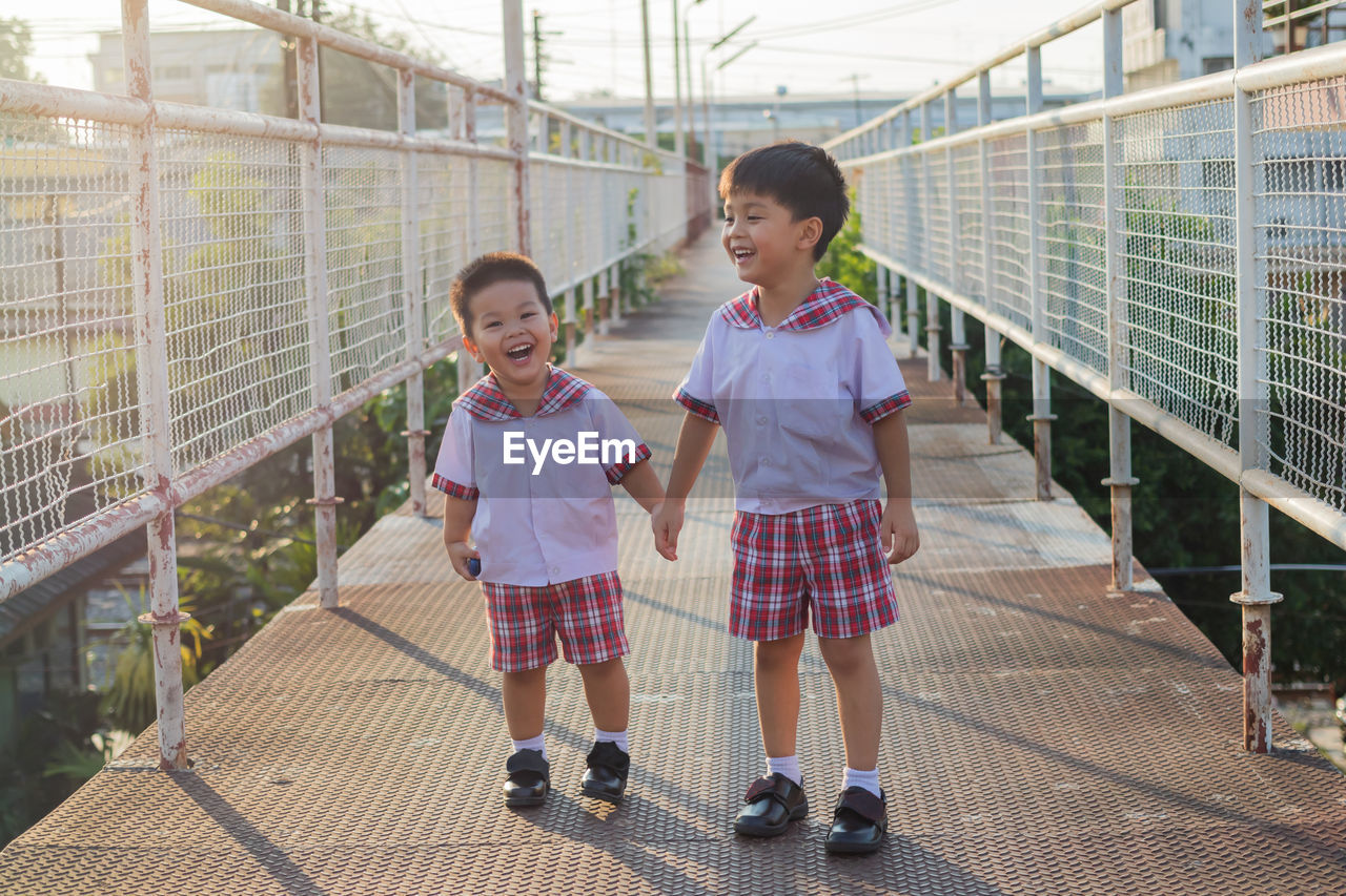 Cute siblings holding hands while standing on footbridge