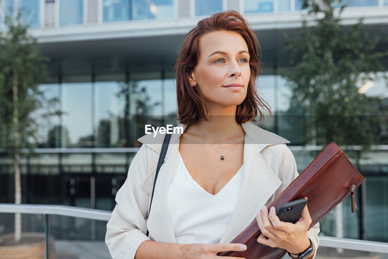 portrait of young woman using mobile phone in city