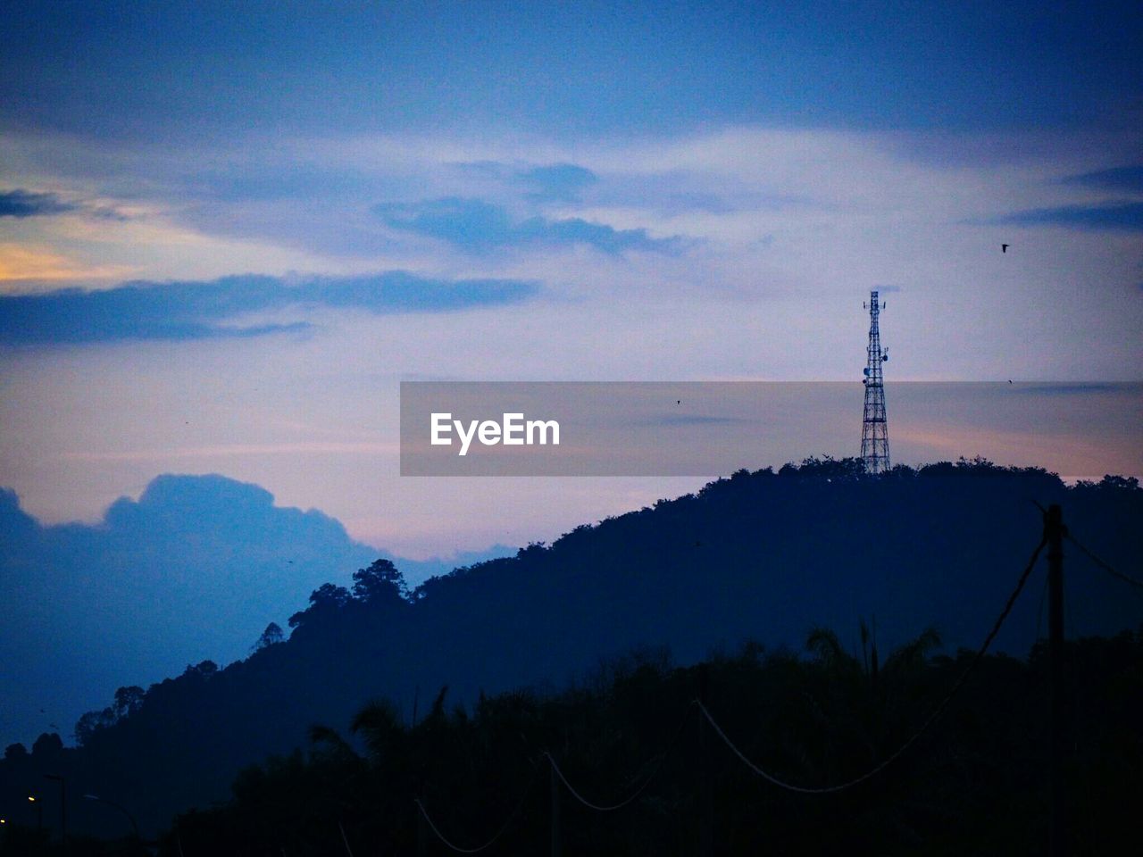 SILHOUETTE OF ELECTRICITY PYLON AGAINST SKY DURING SUNSET