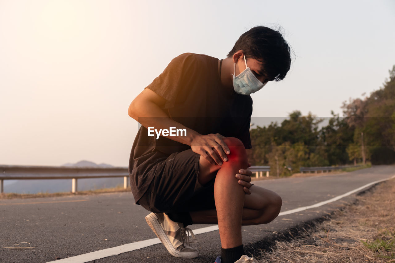 Man sitting on road against sky