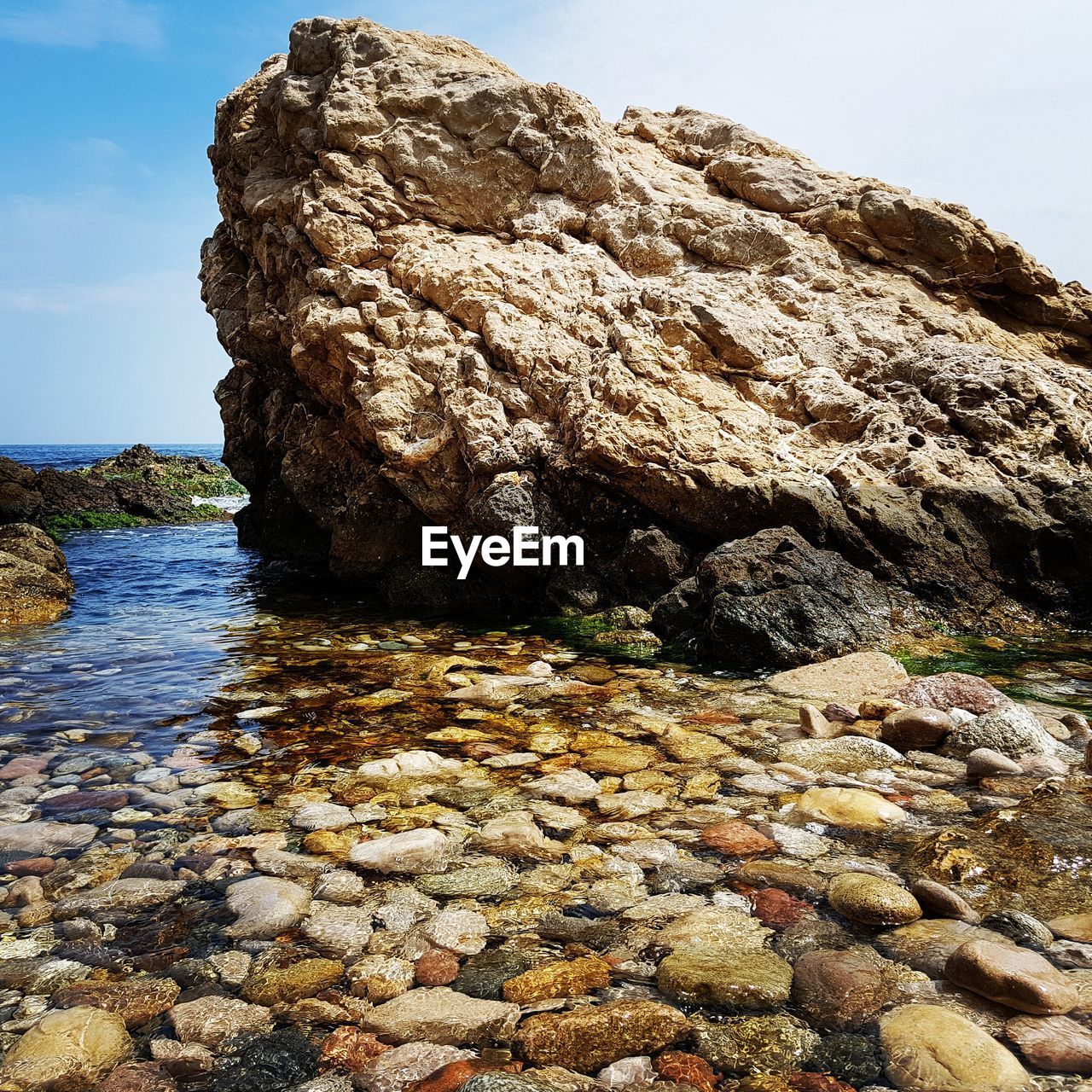 ROCK FORMATIONS AT SHORE AGAINST SKY