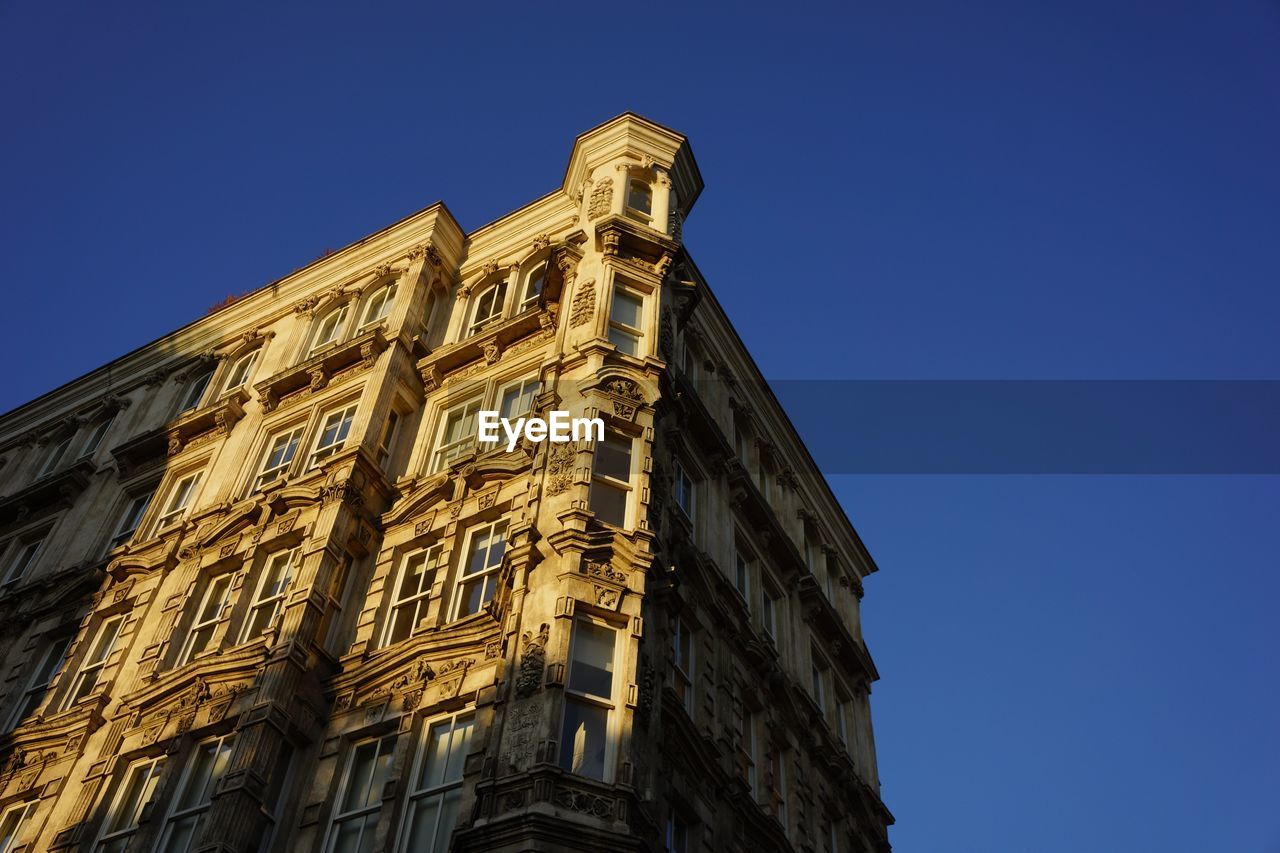 Low angle view of old building against clear blue sky