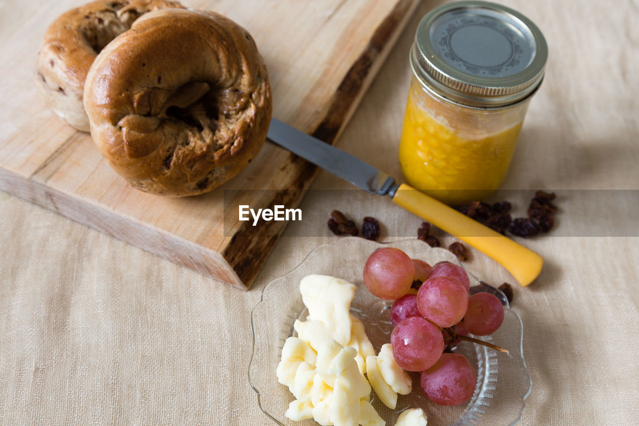 High angle view of healthy foods, including bagels, homemade jam, grapes, cheese curds and raisins