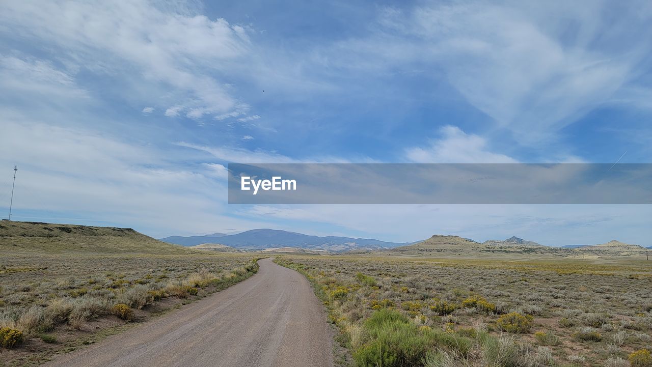 DIRT ROAD ALONG LANDSCAPE AGAINST SKY